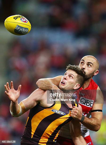 Luke Breust of the Hawks is challenged by Rhyce Shaw of the Swans during the round 16 AFL match between the Sydney Swans and the Hawthorn Hawks at...