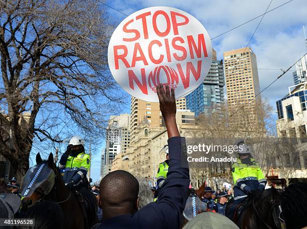 An anti-racism activist holds up a placard as anti-Islam protesters stage rally in Melbourne, Australia on July 18, 2015. Hundreds of police were...