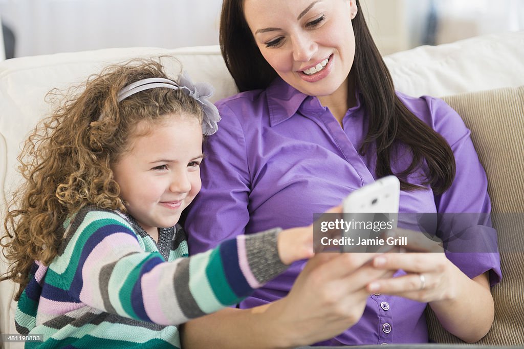 Mother and daughter using mobile phone together