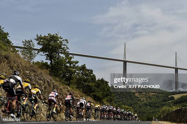 The pack rides near the Millau Viaduct during the 178,5 km fourteenth stage of the 102nd edition of the Tour de France cycling race on July 18...