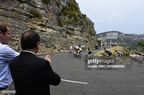 French President Francois Hollande applauds, next to General director of the Tour de France, Christian Prudhomme , as he looks at cyclists riding...