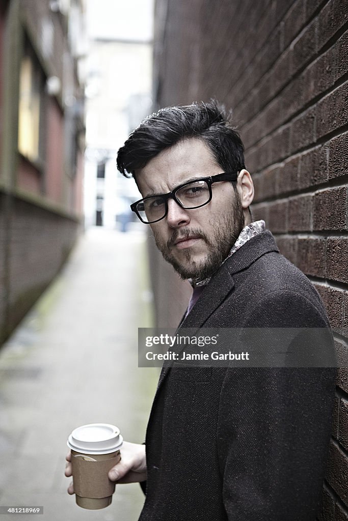 Male holding coffee wearing glasses