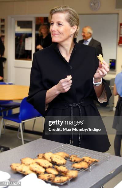 Sophie, Countess of Wessex eats a cookie as she sits in on cookery lesson as she visits the Queensgate Foundation Primary School during a day of...
