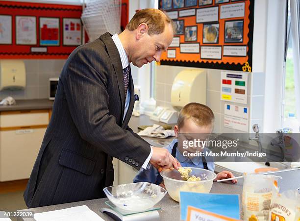 Prince Edward, Earl of Wessex helps a student make cookies as he sits in on cookery lesson whilst visiting the Queensgate Foundation Primary School...