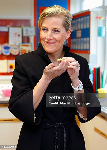 Sophie, Countess of Wessex eats a cookie as she sits in on cookery lesson as she visits the Queensgate Foundation Primary School during a day of...