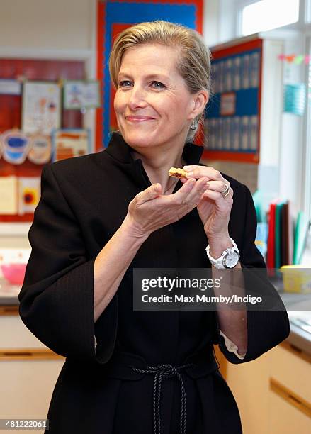 Sophie, Countess of Wessex eats a cookie as she sits in on cookery lesson as she visits the Queensgate Foundation Primary School during a day of...