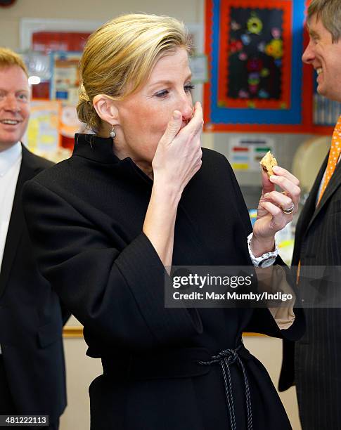 Sophie, Countess of Wessex eats a cookie as she sits in on cookery lesson as she visits the Queensgate Foundation Primary School during a day of...