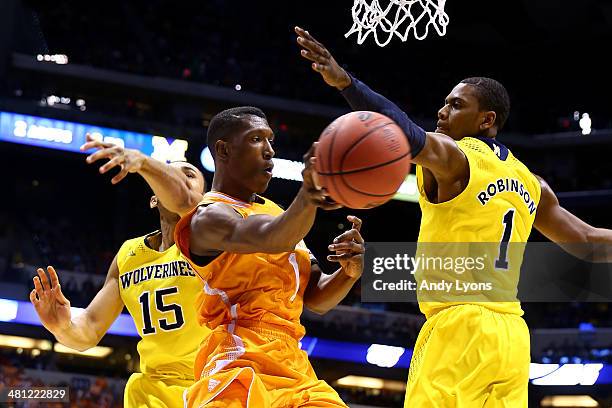 Josh Richardson of the Tennessee Volunteers passes the ball against Glenn Robinson III and Jon Horford of the Michigan Wolverines in the first half...