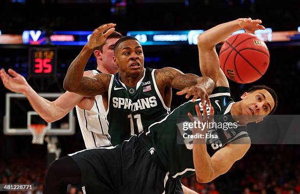 Keith Appling and Travis Trice of the Michigan State Spartans fights for the loose ball against Mike Tobey of the Virginia Cavaliers during the...