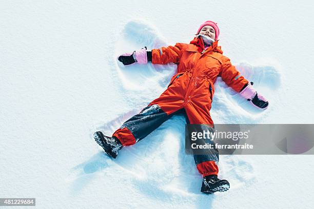 little girl making a snow angel - red jumpsuit stock pictures, royalty-free photos & images