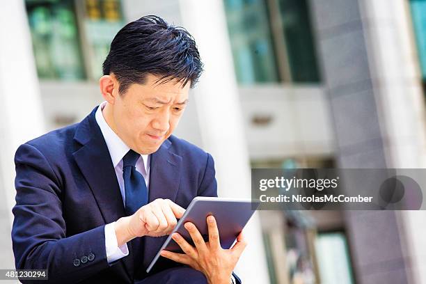 frustré japonais travail hunter recherche d'emploi sur une tablette - exchange rate photos et images de collection