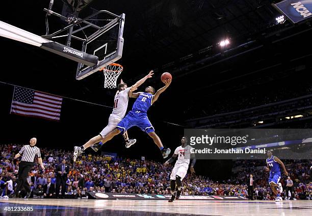 Aaron Harrison of the Kentucky Wildcats shoots the ball over Luke Hancock of the Louisville Cardinals during the regional semifinal of the 2014 NCAA...