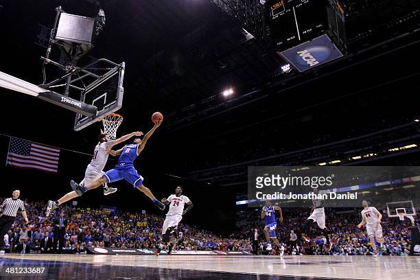 Aaron Harrison of the Kentucky Wildcats shoots the ball over Luke Hancock of the Louisville Cardinals during the regional semifinal of the 2014 NCAA...