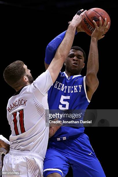 Andrew Harrison of the Kentucky Wildcats gets fouled by Luke Hancock of the Louisville Cardinals during the regional semifinal of the 2014 NCAA Men's...