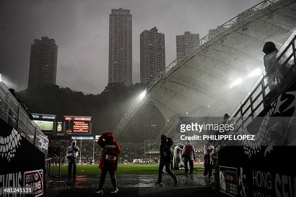 Flood lights illuminate the Hong Kong stadium at noon during a heavy rain storm during the rugby sevens tournament in Hong Kong on March 29, 2014....