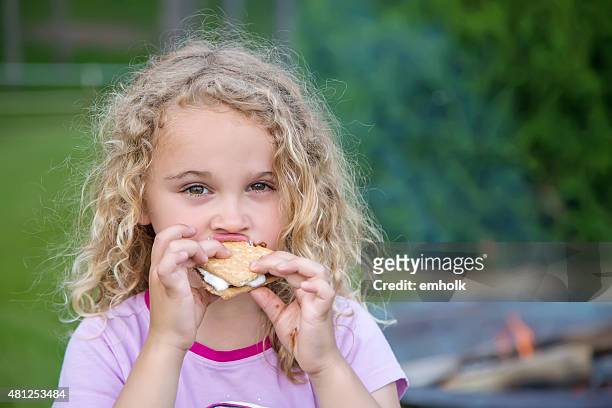 close-up of young girl eating smore near fire - marshmallow stock pictures, royalty-free photos & images