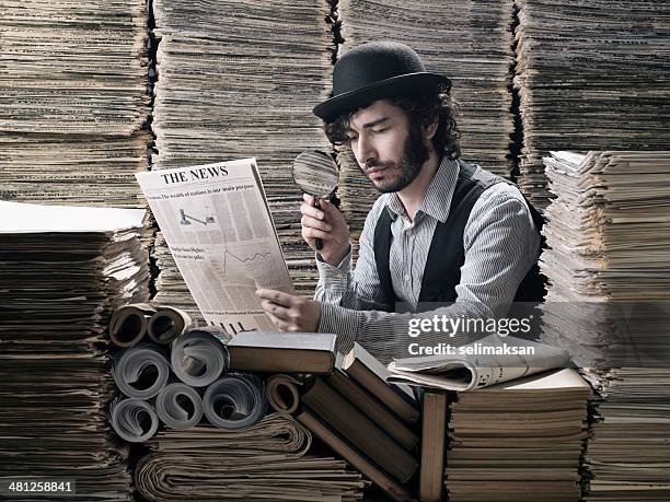 jeune homme en costume à l'ancienne faire des recherches parmi les journaux - détective photos et images de collection