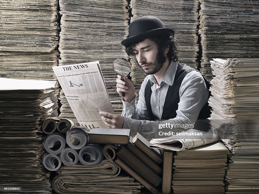 Young man in old fashioned costume doing research among newspapers