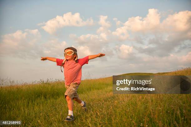 young english boy imagines flying on hill - child pilot stock pictures, royalty-free photos & images