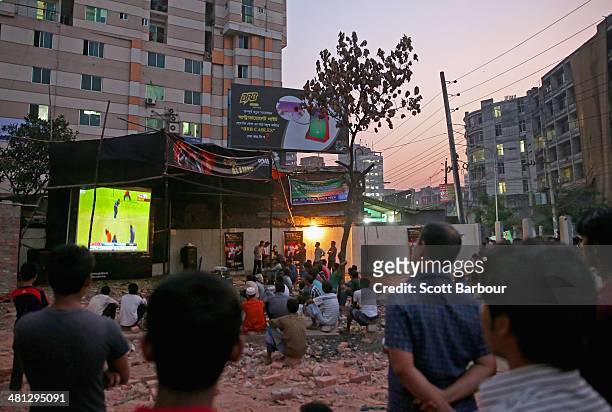 Locals watch the ICC World Twenty20 Bangladesh 2014 Group 1 match between New Zealand and the Netherlands on a large television screen showing the...