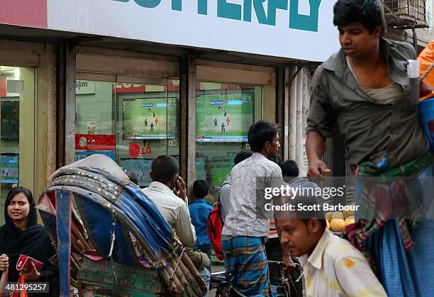 Locals watch the ICC World Twenty20 Bangladesh 2014 Group 1 match between New Zealand and the Netherlands on television screens through the window of...