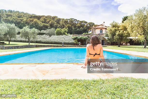 young woman relaxing in a resort swimming pool - villa pool stockfoto's en -beelden