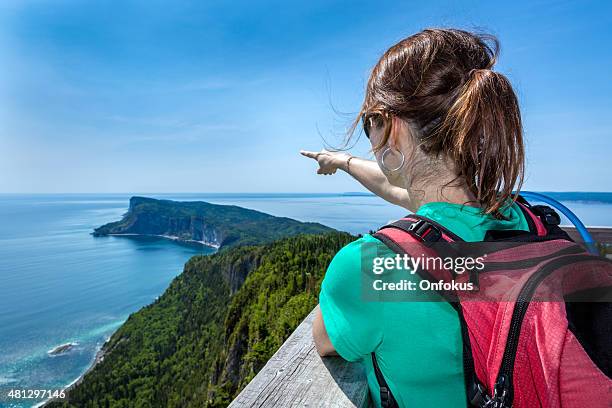 mujer en la cumbre de la montaña señala una dirección - forillon national park fotografías e imágenes de stock