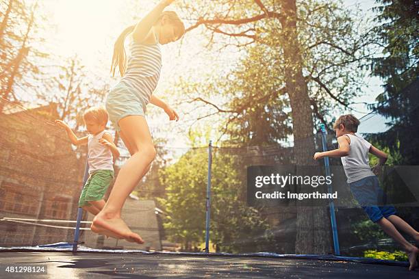 kids jumping on garden trampoline - trampoline jump stock pictures, royalty-free photos & images