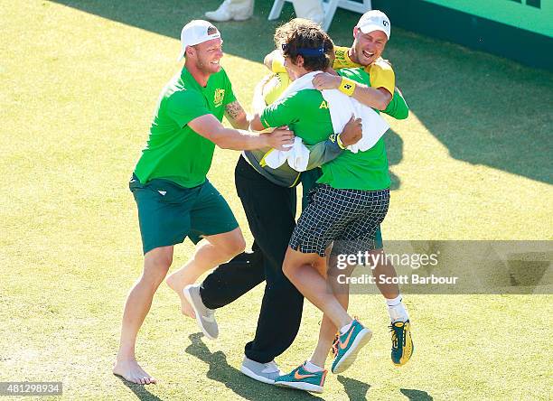 Sam Groth, Thanasi Kokkinakis and Nick Kyrgios run on court to congratulate teammate Lleyton Hewitt of Australia as he celebrates winning the reverse...