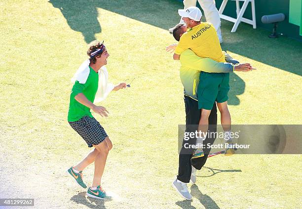 Thanasi Kokkinakis and Nick Kyrgios run on court to congratulate teammate Lleyton Hewitt of Australia as he celebrates winning the reverse singles...