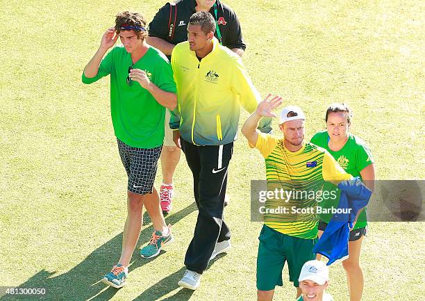 Thanasi Kokkinakis and Nick Kyrgios leave the court as Lleyton Hewitt of Australia celebrates with supporters after winning the reverse singles match...