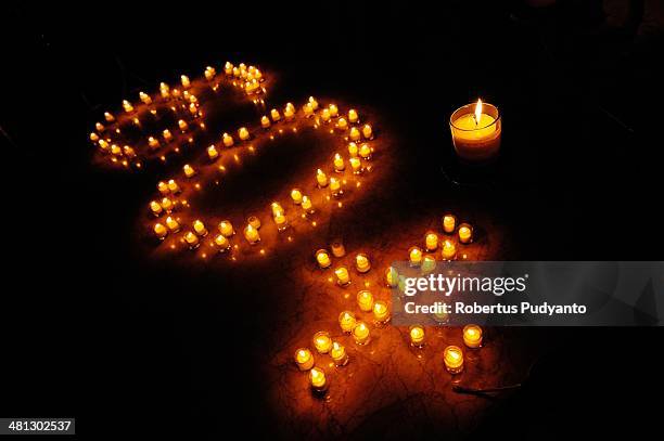 Burning candles stand shaped 60+ during Earth Hour celebration at Sheraton Hotel on March 29, 2014 in Surabaya, Indonesia. Millions of people across...