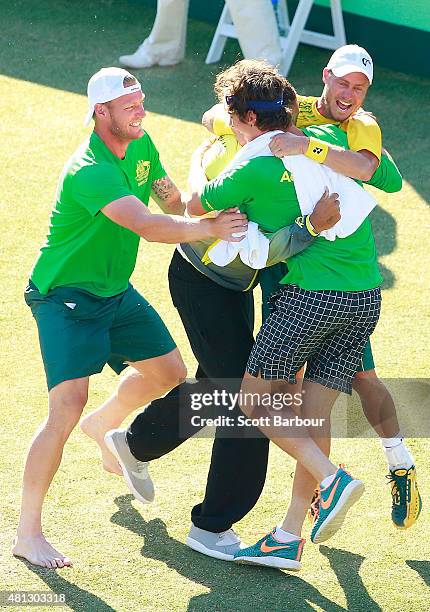 Sam Groth, Thanasi Kokkinakis and Nick Kyrgios run on court to congratulate teammate Lleyton Hewitt of Australia as he celebrates winning the reverse...