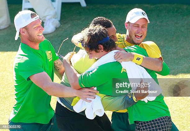 Sam Groth, Thanasi Kokkinakis and Nick Kyrgios run on court to congratulate teammate Lleyton Hewitt of Australia as he celebrates winning the reverse...