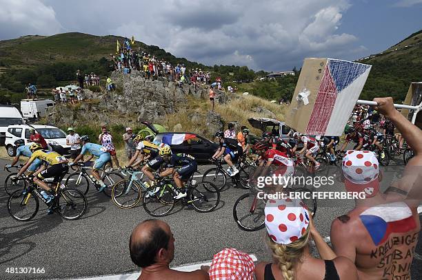 Great Britain's Christopher Froome , wearing the overall leader's yellow jersey, rides in the pack past supporters cheering during the 183 km...