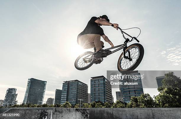 bmx rider jumping in urban environment - bmx freestyle stock pictures, royalty-free photos & images