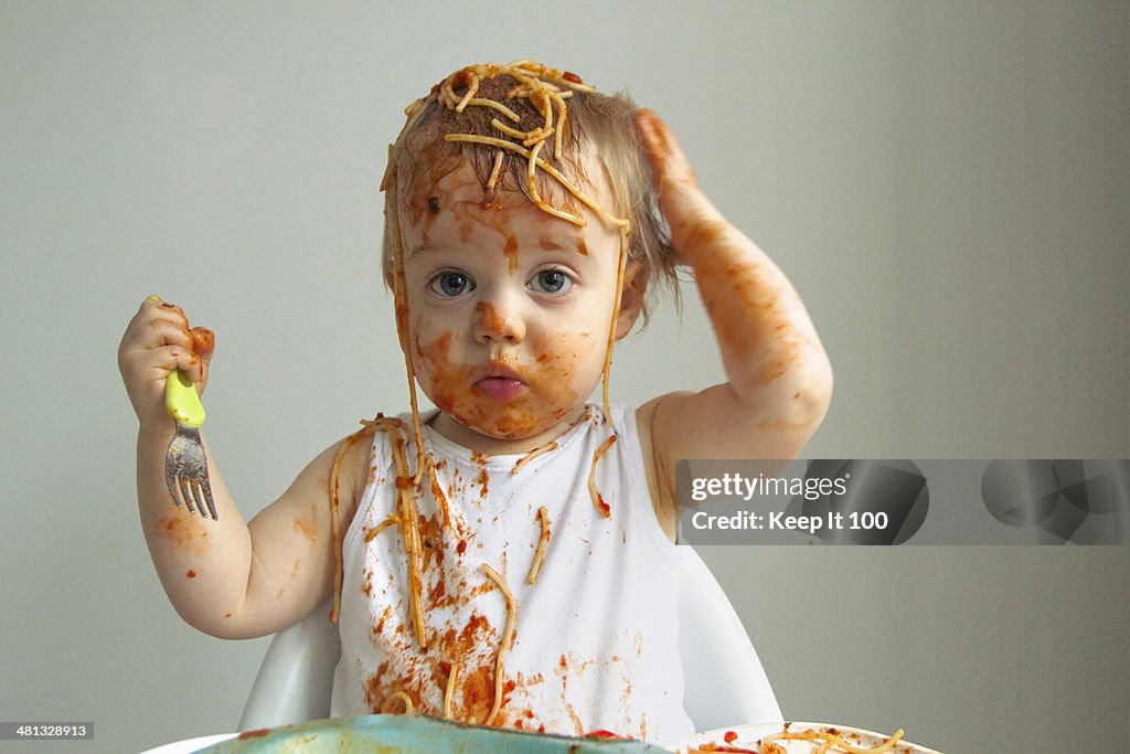 Baby boy getting messy eating spaghetti