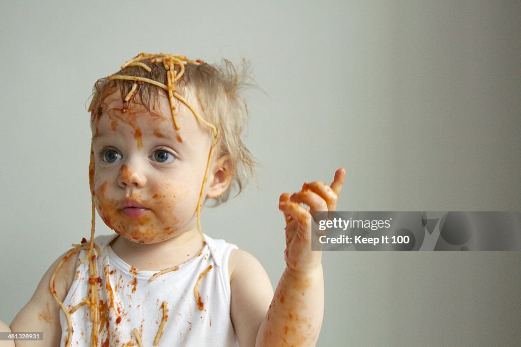 Baby boy getting messy eating spaghetti