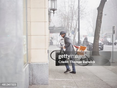 Businessman lifting bicycle up steps into building Businessman lifting bicycle up steps into building