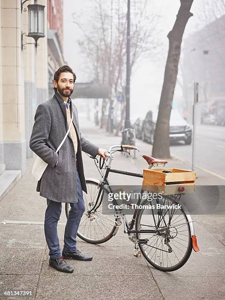 Smiling businessman standing next to bike