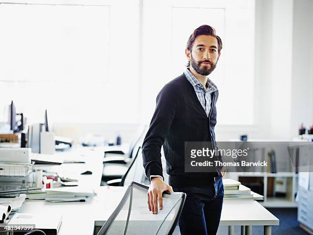 smiling professional standing at workstation - dreiviertelansicht stock-fotos und bilder