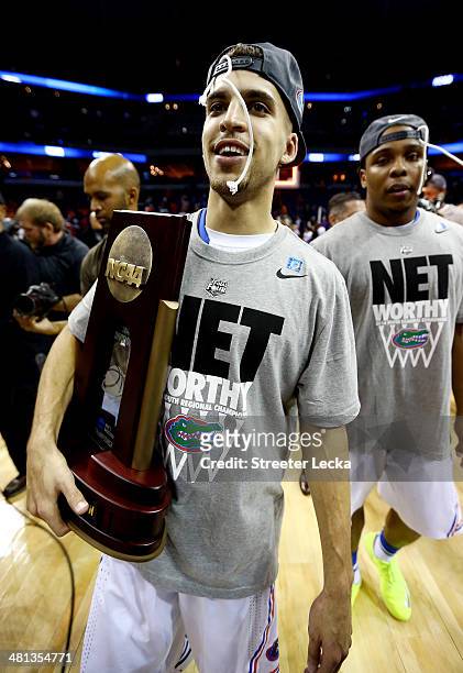 Scottie Wilbekin of the Florida Gators celebrates on the court with the trophy after defeating the Dayton Flyers 62-52 in the south regional final of...