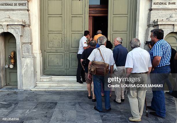 People enter a branch of a national bank in Athens on July 20, 2015. Greek banks reopened after a three-week shutdown imposed to stop mass cash...