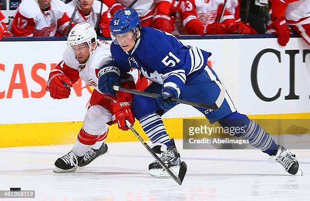 Jake Gardiner of the Toronto Maple Leafs battles for the puck against Luke Glendening of the Detroit Red Wings during NHL action at the Air Canada...