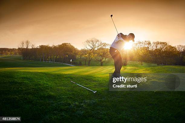 backlit golf course with golfer chipping onto green - golfing stockfoto's en -beelden