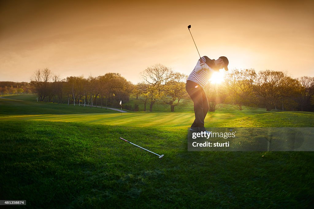 Backlit golf course with golfer chipping onto green