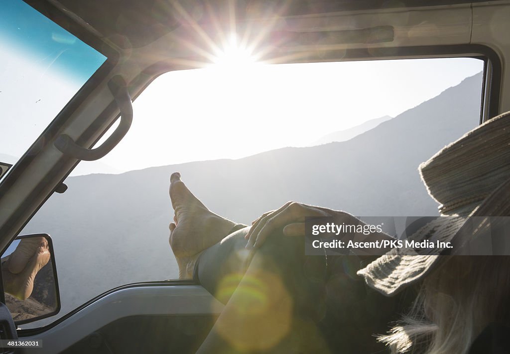 Woman relaxes in vehicle, feet stretched to sun