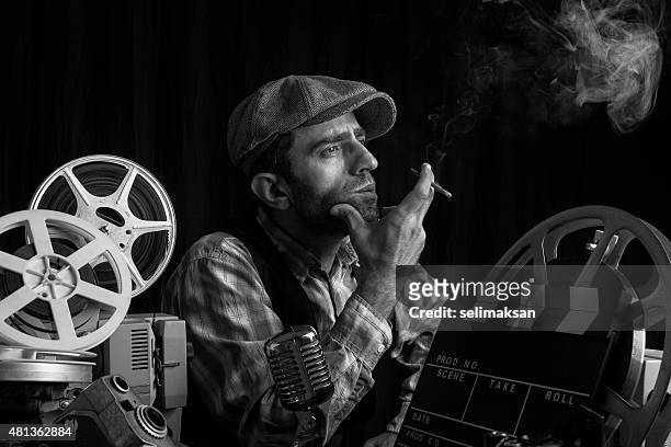 old fashioned film director posing with cinema equipments and smoking - film director stock pictures, royalty-free photos & images