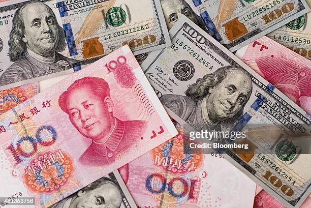 One-hundred dollar bills and Chinese one-hundred yuan banknotes are arranged for a photograph in Hong Kong, China, on Monday, July 20, 2015. The yuan...