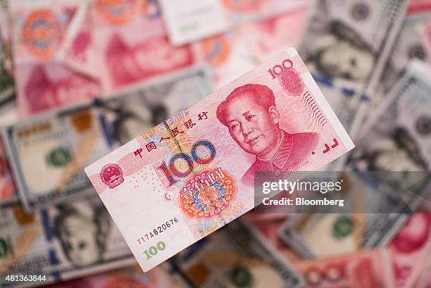 Chinese one-hundred yuan banknote sits on a pile of U.S. One-hundred dollar bills and Chinese one-hundred yuan banknotes in this arranged photograph...